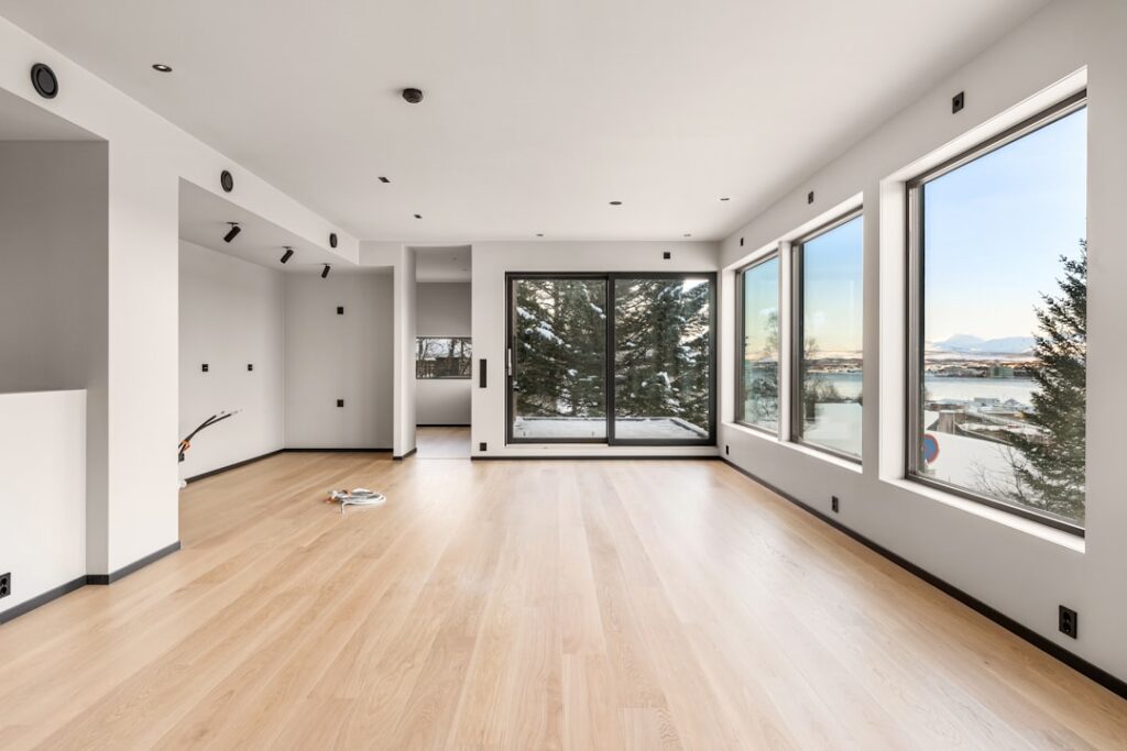 Large, modern living room with minimal furniture, conveying a sense of quiet and unused space.