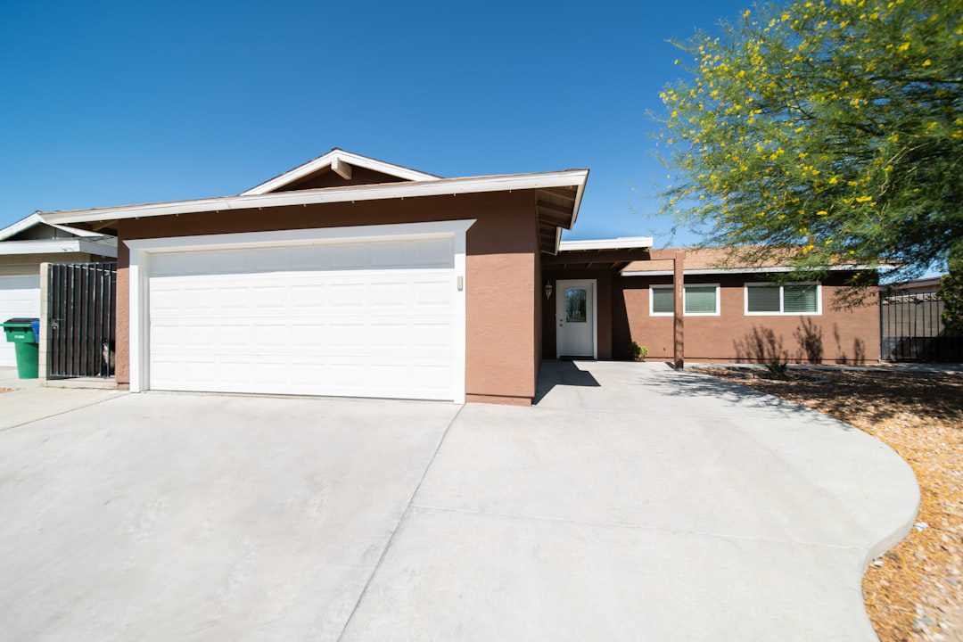 The bright, sunny exterior of a modern suburban home with a manicured lawn and clean architectural lines, representing a valuable real estate asset.