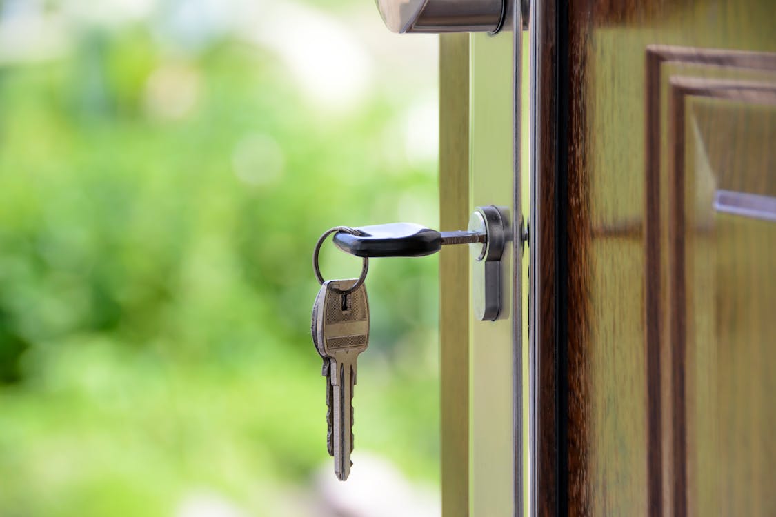 A close-up of a professional handshake between a real estate agent and a client over a table with house keys, symbolizing trust and a satisfactory agreement.
