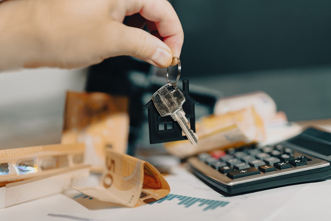 A close-up shot of a real estate agent's hand giving house keys to another person, symbolizing a smooth and successful property sale for a landlord.