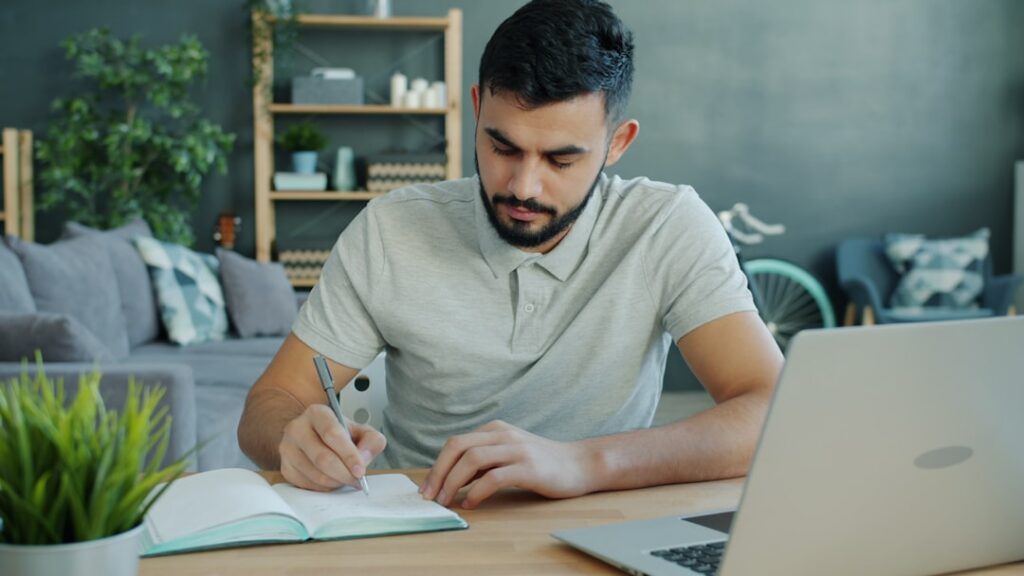 Concerned homeowner sits at a table in a modern, brightly lit home, carefully reviewing financial documents related to the...