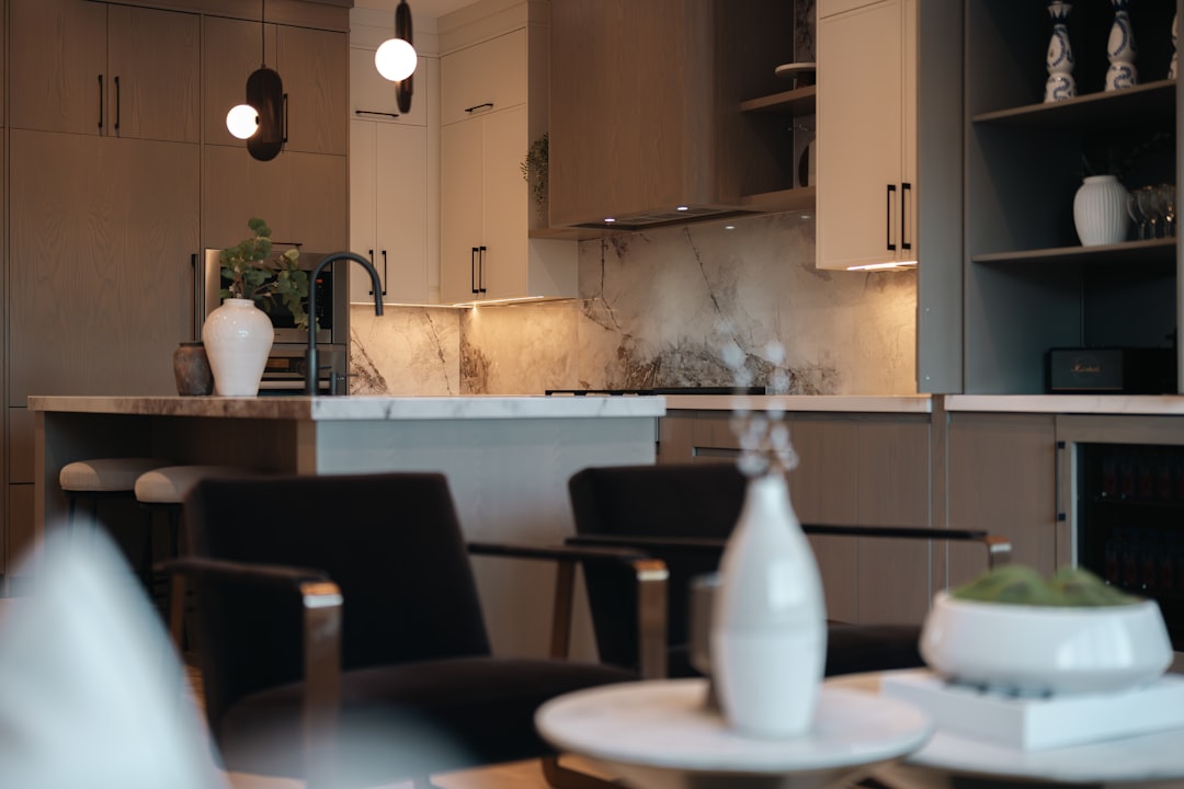 A professional real estate agent sits at a table in a bright, modern home, focused on their laptop, illustrating a data-driven approach to property pricing.