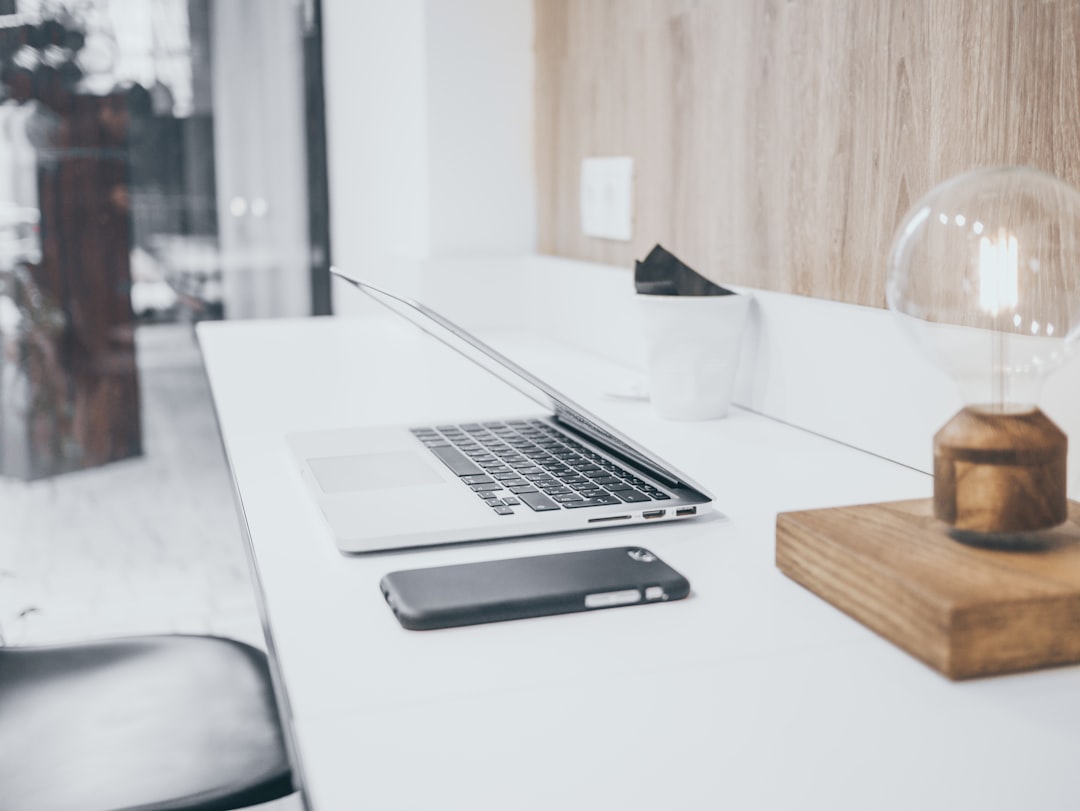 A real estate professional's clean, modern desk with a laptop, tablet, and smartphone working in unison, symbolizing a powerful and efficient marketing engine.