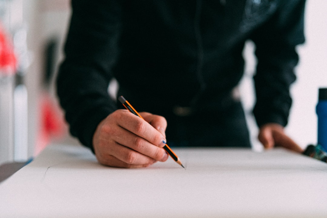 Close-up of an architect's hands meticulously drawing on housing blueprints with a ruler, symbolizing a data-driven and precise approach to real estate transactions.