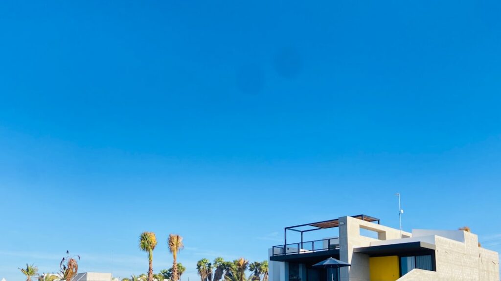 Real estate 'Sold' sign in the front yard of a modern, attractive suburban home under a bright, sunny sky, symbolizing a q...