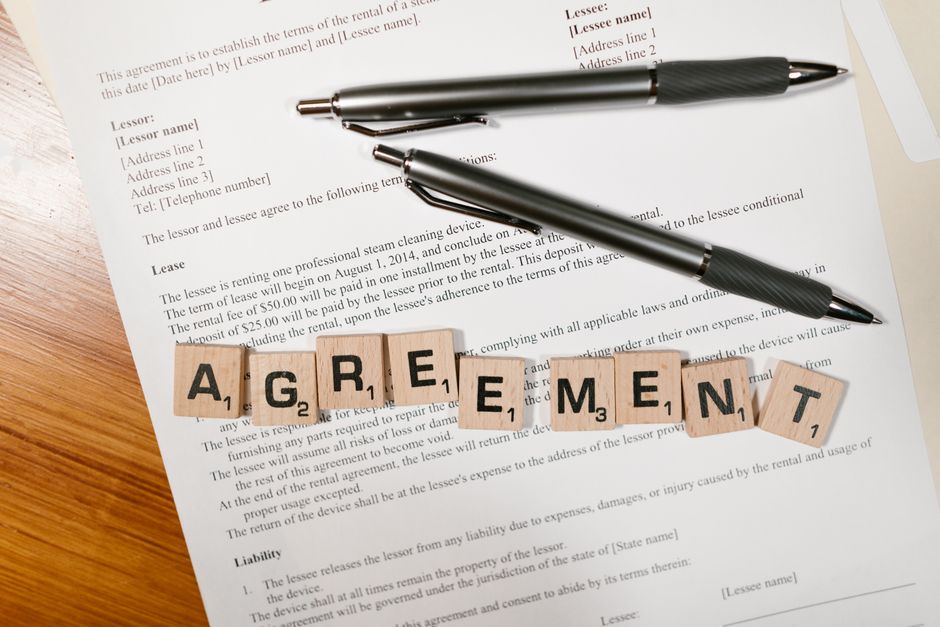 A close-up of house keys and a pen resting on a real estate contract, representing the successful and stress-free closing process managed by a specialist team.