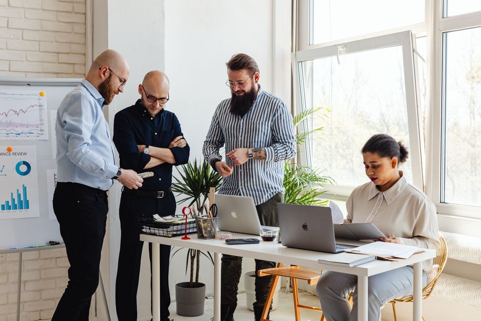 Diverse group of seven real estate specialists collaborating around a table in a bright, modern office, symbolizing the te...
