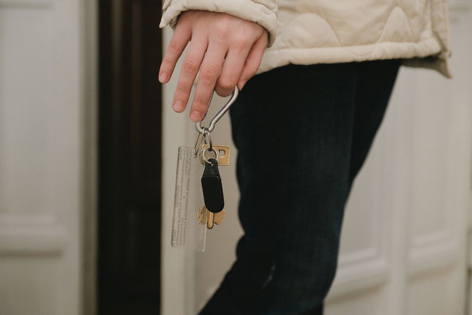 A person's hand holding a set of keys and unlocking the front door of a welcoming, modern home, symbolizing new ownership.