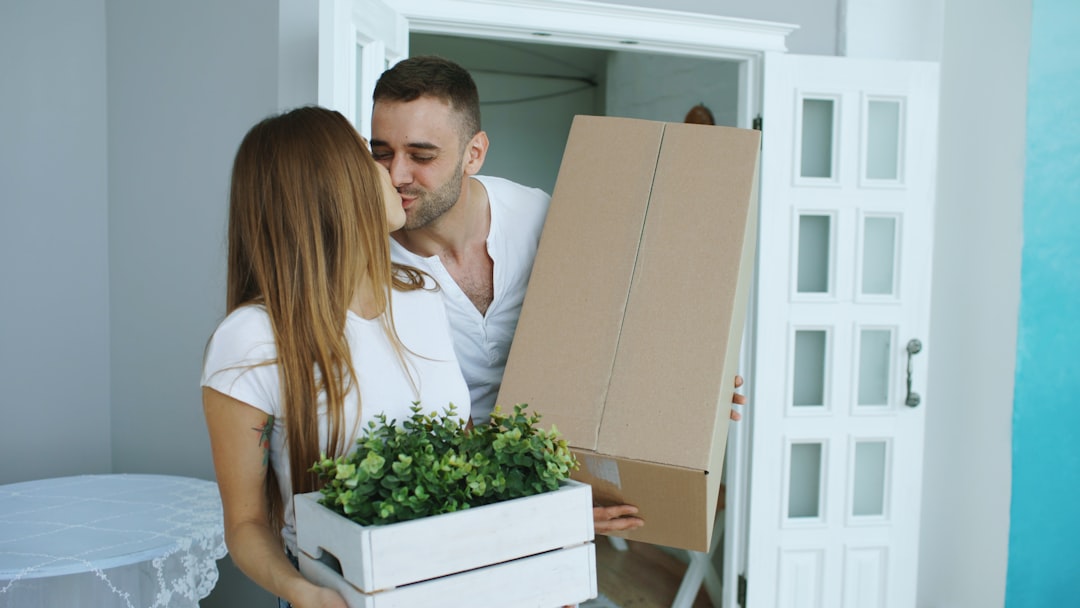 A smiling family works together to carry moving boxes into their beautiful new modern home, illustrating a successful and stress-free transition to a new property.