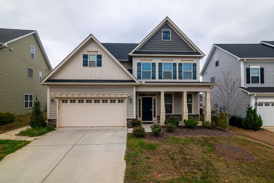 A beautiful modern suburban home with excellent curb appeal, featuring clean lines, large windows, and a manicured lawn under a bright, sunny sky.