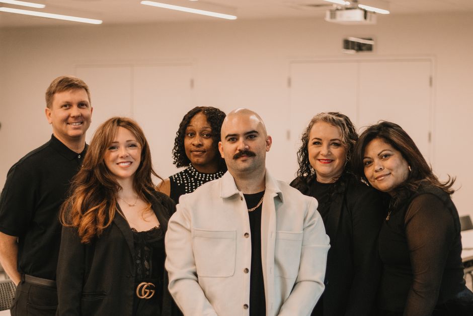 Diverse team of professional real estate agents gathered around a large table in a bright, modern office, collaborating on...