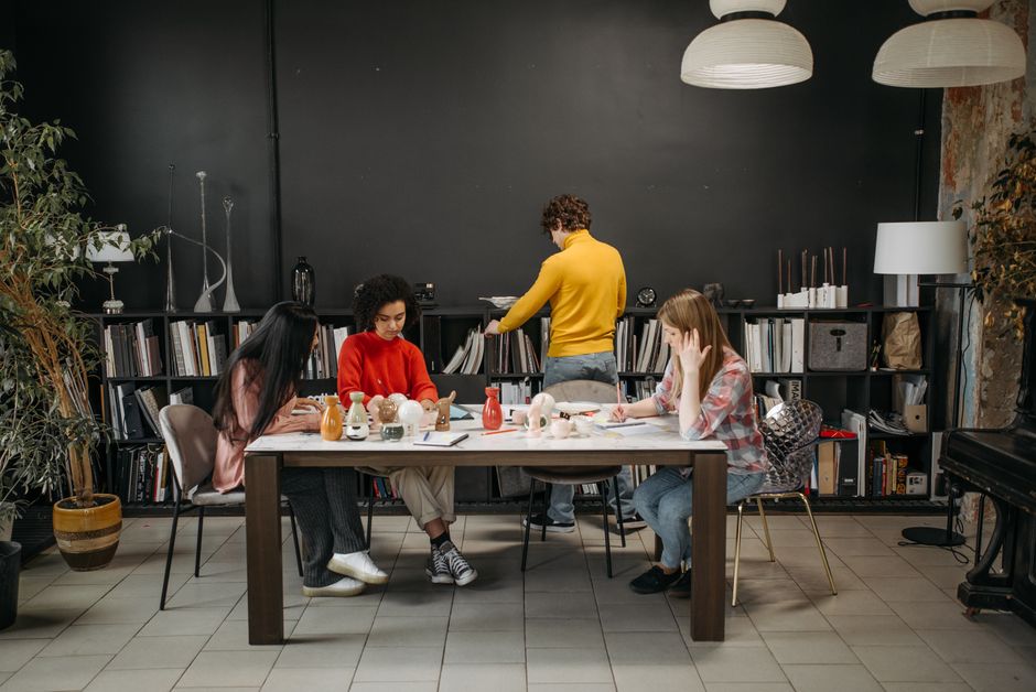 A diverse team of professionals in a bright, modern office collaborating around a table, illustrating a coordinated blueprint for a complex project.