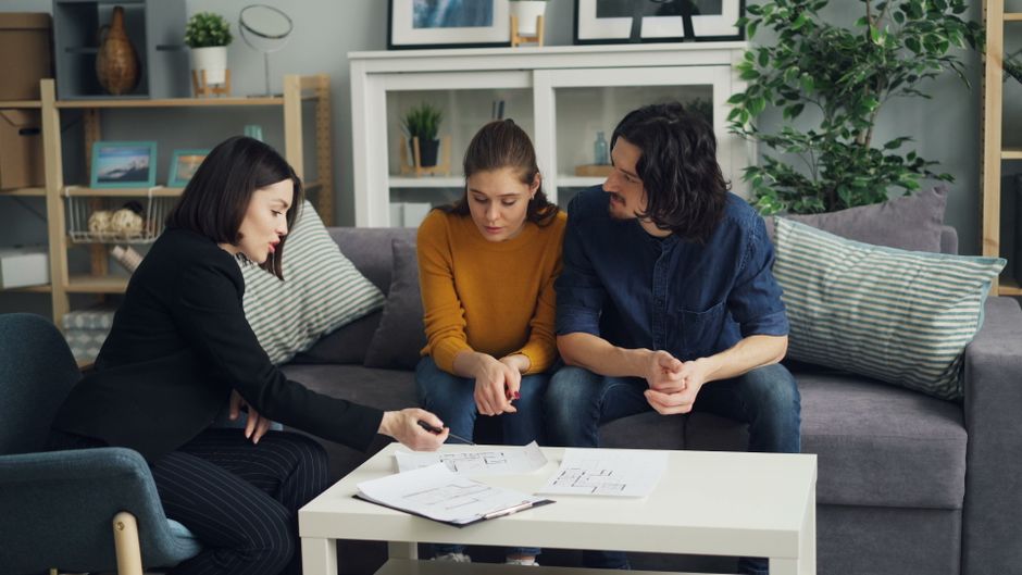 Real estate professional reviews a digital marketing strategy on a tablet, with the clean interior of a modern home blurre...